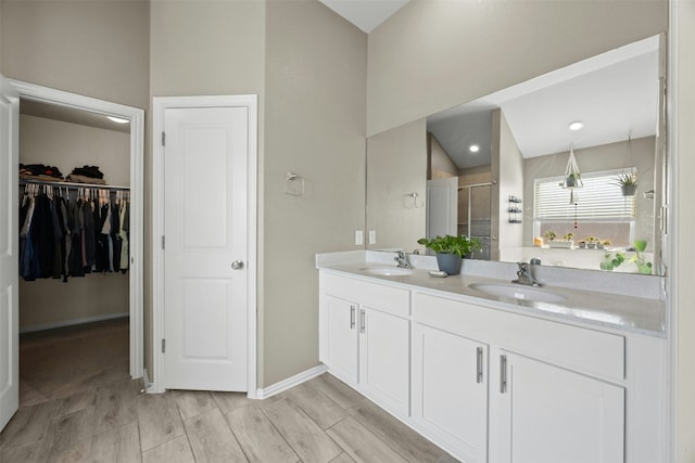 bathroom featuring walk in shower, lofted ceiling, and vanity