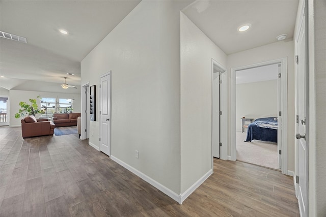 hall with lofted ceiling and light hardwood / wood-style floors