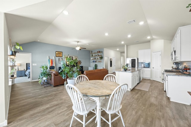 dining space featuring ceiling fan, lofted ceiling, and light wood-type flooring