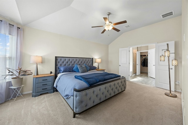 bedroom featuring ceiling fan, light colored carpet, a spacious closet, and vaulted ceiling