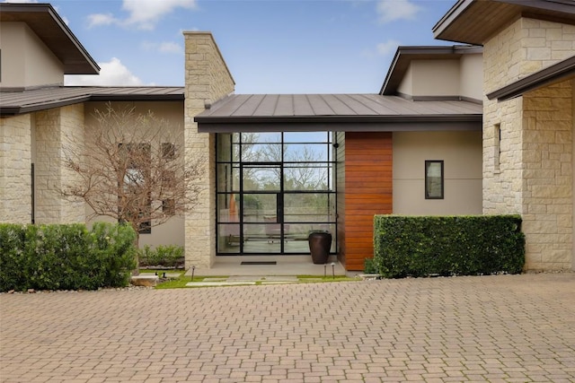 entrance to property featuring a standing seam roof, metal roof, and stucco siding