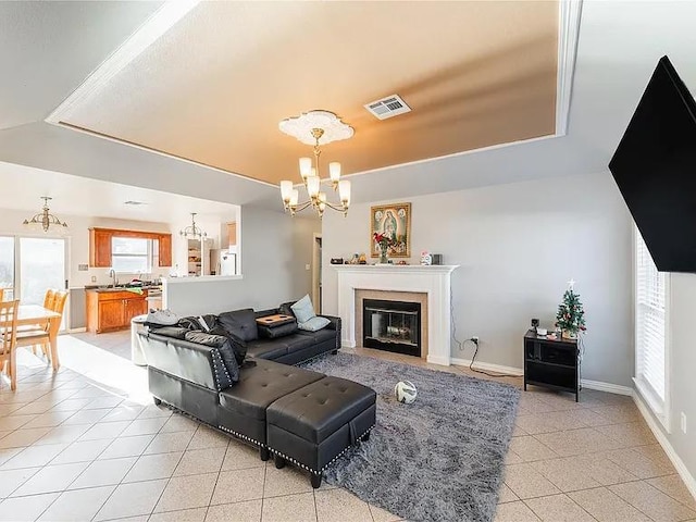 living room with an inviting chandelier, light tile patterned floors, a tray ceiling, and sink