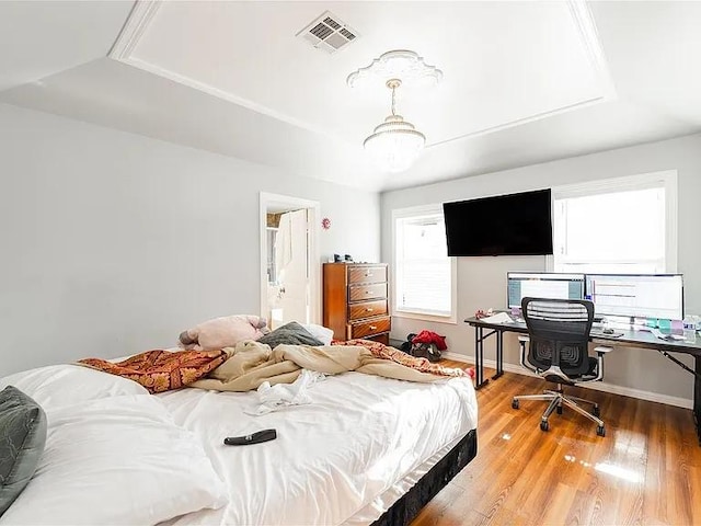 bedroom with wood-type flooring and a tray ceiling