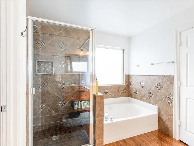 bathroom featuring tile walls, hardwood / wood-style flooring, and shower with separate bathtub