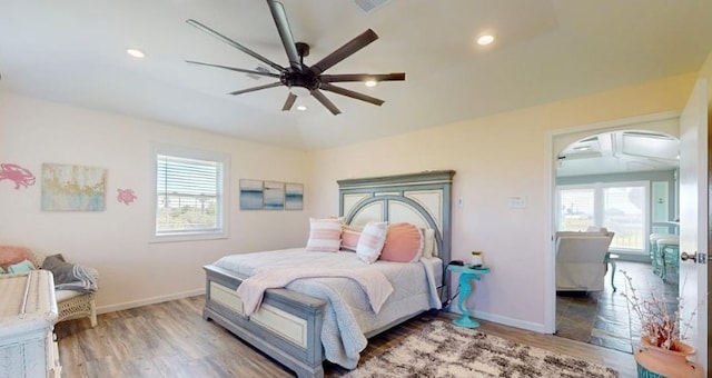 bedroom featuring multiple windows, lofted ceiling, hardwood / wood-style flooring, and ceiling fan