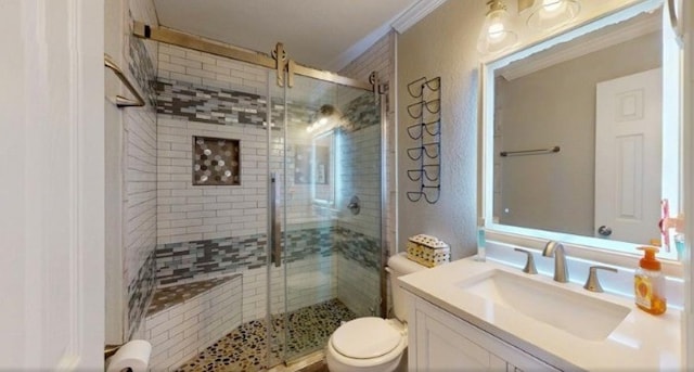 bathroom with a shower with door, vanity, ornamental molding, and toilet