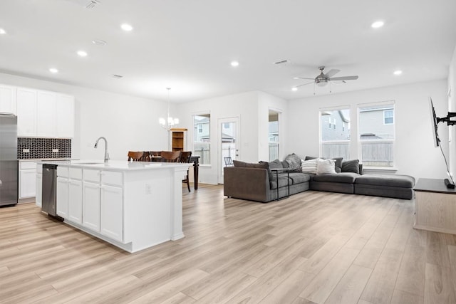 kitchen featuring stainless steel appliances, white cabinetry, a kitchen island with sink, and decorative light fixtures