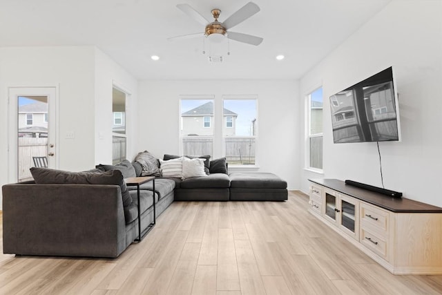 living room with plenty of natural light, light hardwood / wood-style floors, and ceiling fan