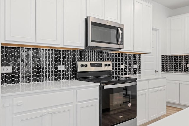 kitchen with tasteful backsplash, stainless steel appliances, light hardwood / wood-style floors, and white cabinets