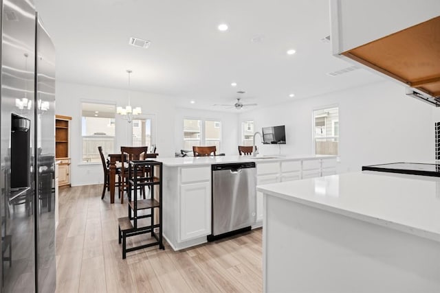 kitchen featuring light hardwood / wood-style flooring, hanging light fixtures, a kitchen island, stainless steel appliances, and white cabinets