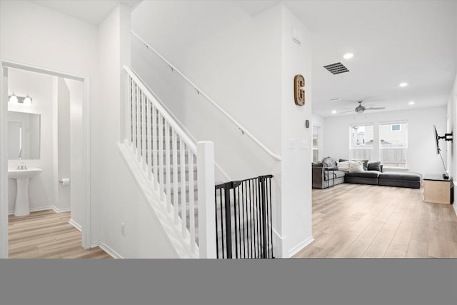 stairway with sink, hardwood / wood-style floors, and ceiling fan