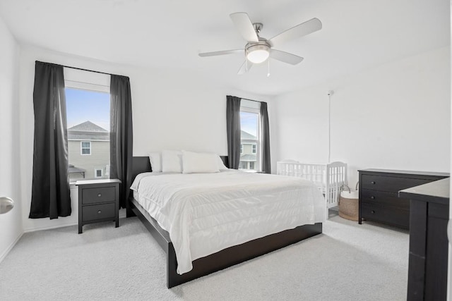 bedroom featuring multiple windows, light carpet, and ceiling fan