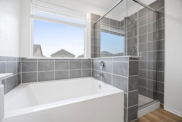 bathroom featuring wood-type flooring and shower with separate bathtub