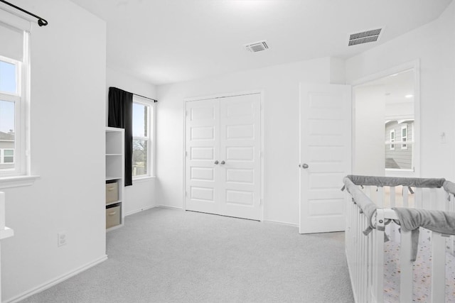 unfurnished bedroom featuring light carpet, multiple windows, and a closet