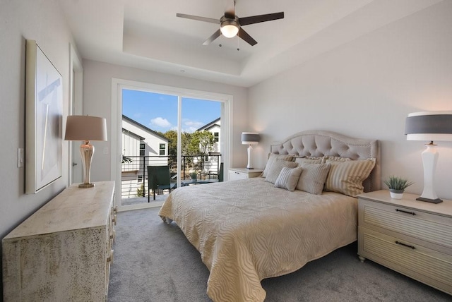 carpeted bedroom featuring ceiling fan, a tray ceiling, and access to exterior