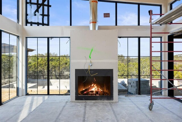 4600 Wild Cow Cv, Spicewood, TX 78669 - unfurnished living room featuring a high ceiling and a lit fireplace