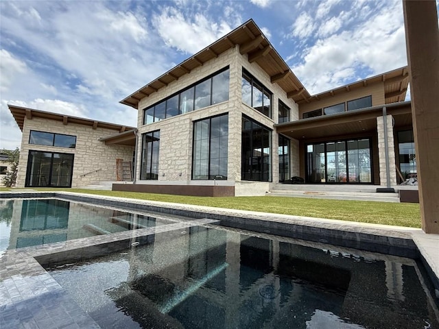4600 Wild Cow Cv, Spicewood, TX 78669 - rear view of house with a pool with connected hot tub, stone siding, and a yard