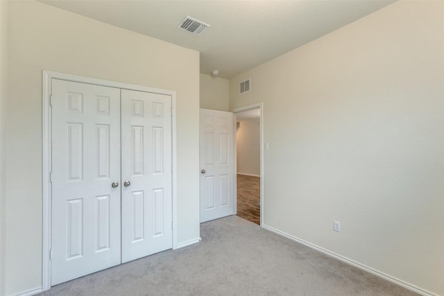 unfurnished bedroom featuring light carpet and a closet