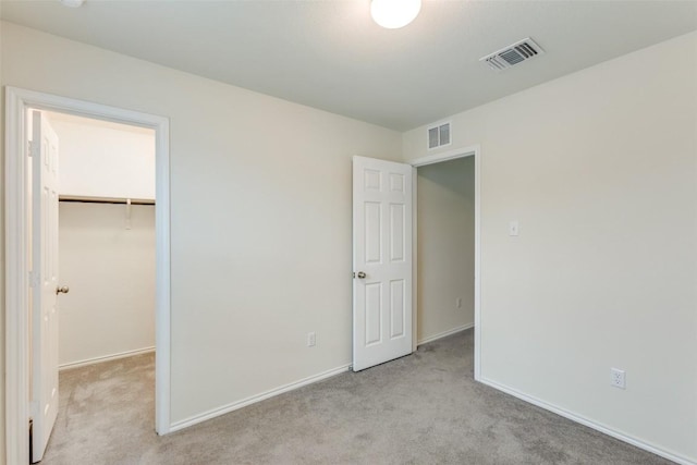 unfurnished bedroom featuring a spacious closet, light carpet, and a closet