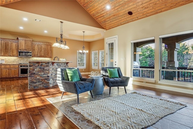 living area featuring dark wood-type flooring, high vaulted ceiling, a tray ceiling, wooden ceiling, and a chandelier