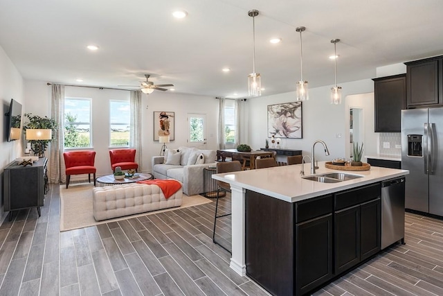 kitchen with sink, a breakfast bar area, hanging light fixtures, a kitchen island with sink, and stainless steel appliances