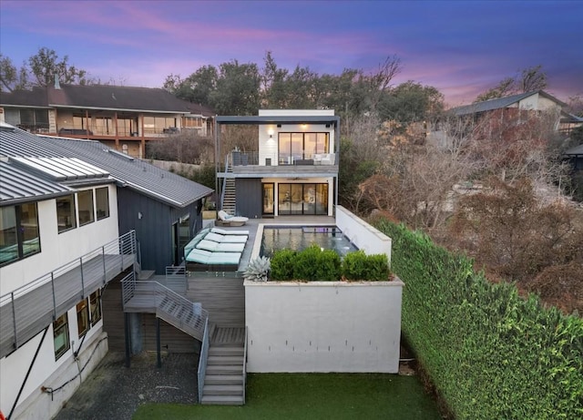 back house at dusk featuring a balcony