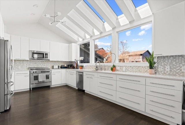 kitchen with appliances with stainless steel finishes, dark wood-type flooring, vaulted ceiling with skylight, and white cabinets