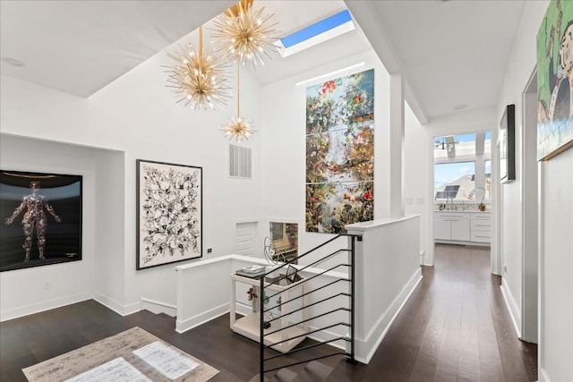 hallway with a skylight, dark hardwood / wood-style floors, and a chandelier