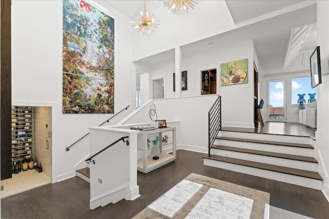 staircase featuring hardwood / wood-style flooring, a towering ceiling, and an inviting chandelier