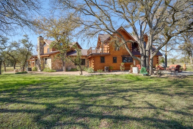 rear view of property with a patio area, a lawn, and log siding