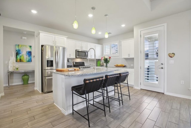 kitchen with decorative backsplash, wood finish floors, white cabinetry, and stainless steel appliances