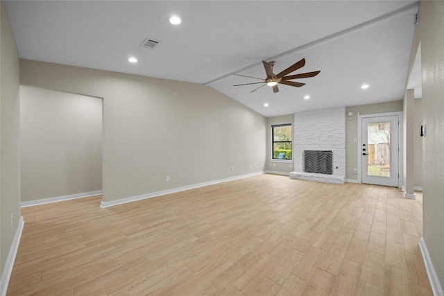 unfurnished living room featuring ceiling fan, lofted ceiling, a stone fireplace, and light hardwood / wood-style flooring