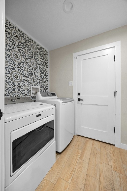 clothes washing area featuring light hardwood / wood-style flooring and washing machine and dryer