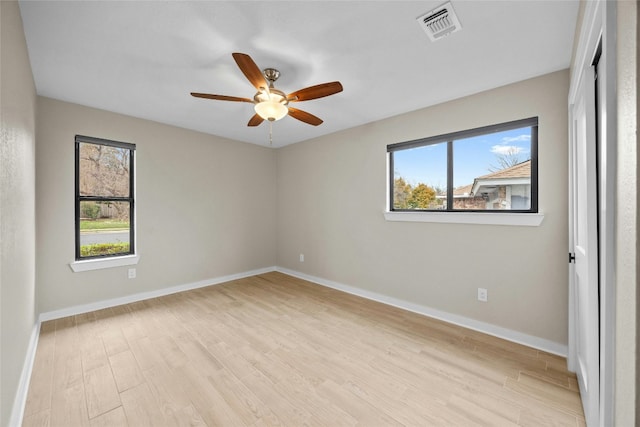 empty room with ceiling fan, light hardwood / wood-style floors, and a healthy amount of sunlight