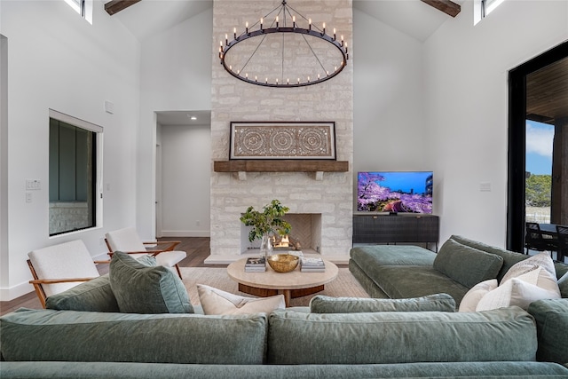 living room with wood-type flooring, a large fireplace, a notable chandelier, and high vaulted ceiling