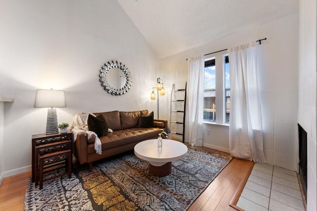 5608 Cougar Dr Unit 220, Austin, TX 78745 - living area featuring vaulted ceiling, wood finished floors, baseboards, and a tiled fireplace
