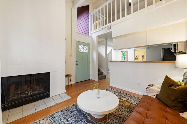5608 Cougar Dr Unit 220, Austin, TX 78745 - living area with wood finished floors, stairs, a towering ceiling, a tiled fireplace, and baseboards