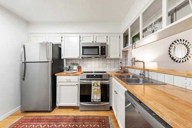 5608 Cougar Dr Unit 220, Austin, TX 78745 - kitchen featuring appliances with stainless steel finishes, a sink, light wood finished floors, tasteful backsplash, and white cabinetry