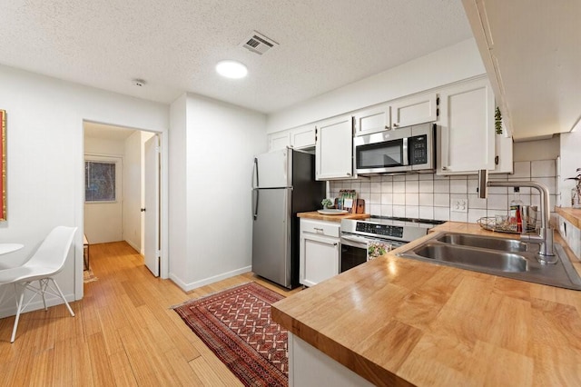 5608 Cougar Dr Unit 220, Austin, TX 78745 - kitchen with appliances with stainless steel finishes, a sink, white cabinetry, decorative backsplash, and light wood finished floors