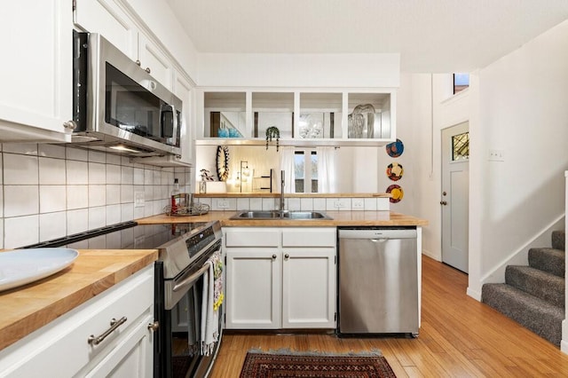 5608 Cougar Dr Unit 220, Austin, TX 78745 - kitchen featuring appliances with stainless steel finishes, a sink, a peninsula, backsplash, and light wood-style floors