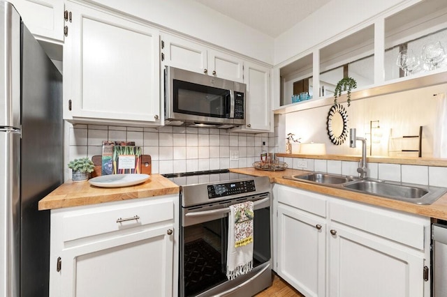 5608 Cougar Dr Unit 220, Austin, TX 78745 - kitchen with stainless steel appliances, a sink, butcher block countertops, decorative backsplash, and white cabinets