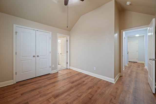 unfurnished bedroom with lofted ceiling, ceiling fan, a closet, and hardwood / wood-style flooring