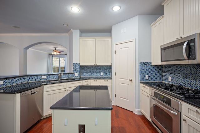 kitchen featuring appliances with stainless steel finishes, sink, a kitchen island, dark hardwood / wood-style flooring, and decorative backsplash