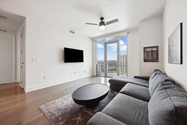 living room with ceiling fan, a wall of windows, and hardwood / wood-style floors