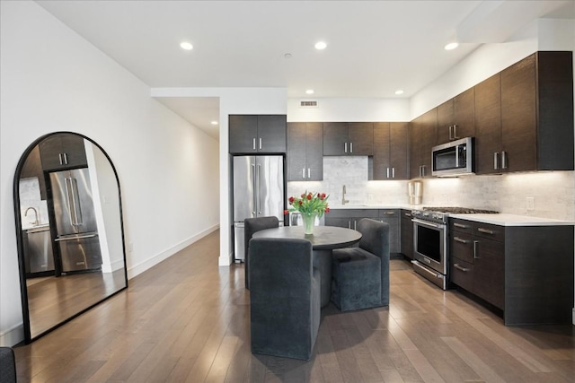 222 W Ave Unit 1312, Austin, TX 78701 - kitchen featuring high quality appliances, light countertops, dark brown cabinetry, light wood-type flooring, and recessed lighting