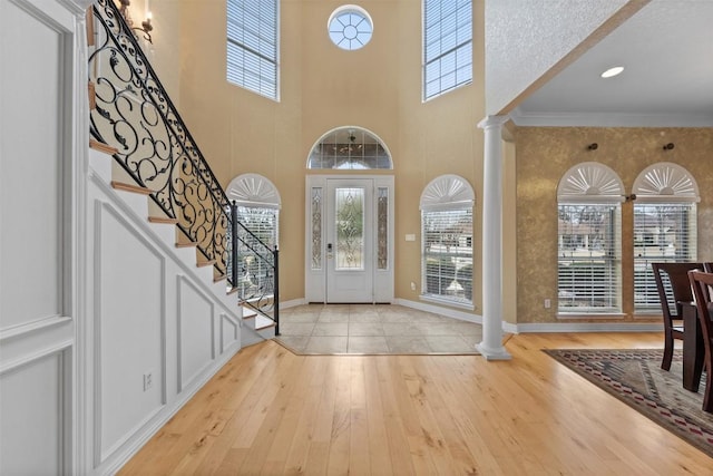 foyer with ornamental molding, decorative columns, and light hardwood / wood-style flooring