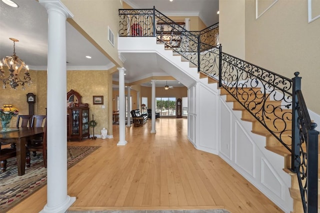 foyer featuring ceiling fan with notable chandelier, ornamental molding, decorative columns, and light hardwood / wood-style floors