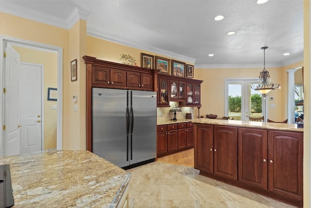 kitchen with stainless steel fridge, hanging light fixtures, ornamental molding, light stone counters, and french doors