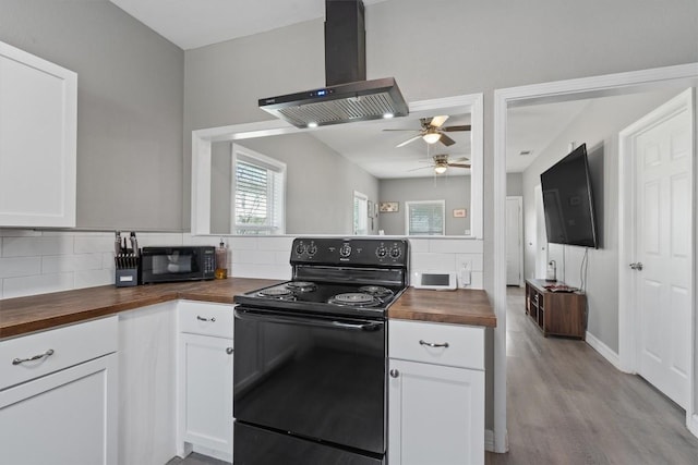 kitchen with wood counters, white cabinetry, ventilation hood, and black appliances