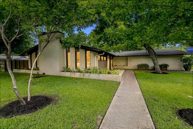 mid-century modern home featuring brick siding and a front lawn